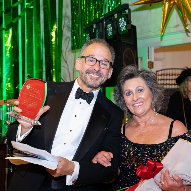 Smiling couple holding up award.
